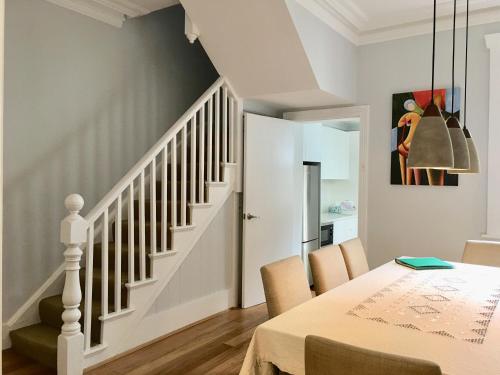 Un comedor con una mesa y una escalera. en 3BR Terrace House in Darling Habour, next to ICC and The Star, Sydney CBD, Free parking, en Sídney