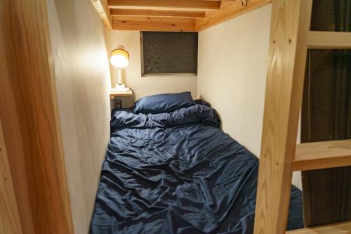 a small bed in a small room with a ladder at ゲストハウス さんかくワサビ in Saiki