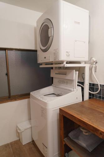 a washing machine with a microwave on top of it at ゲストハウス さんかくワサビ Guest house Sankaku Wasabi in Saiki