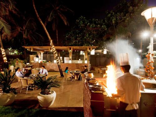 a chef standing in front of a restaurant with a fire at Novotel Mumbai Juhu Beach in Mumbai
