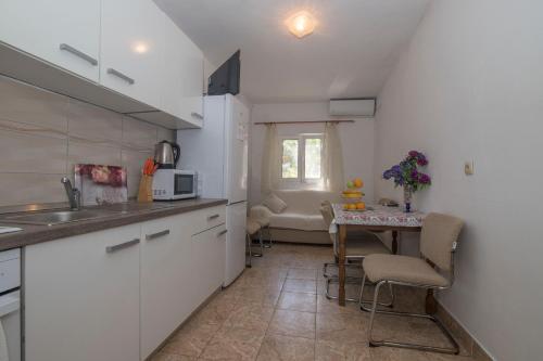 a kitchen with a small table and a kitchen with white cabinets at Apartments Ante in Bogomolje