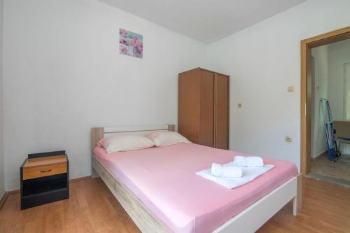a bedroom with a bed with pink sheets and a dresser at Apartments Ante in Bogomolje