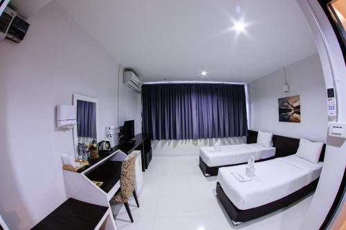 a hotel room with two beds and a table at The Train Hotel Hatyai in Hat Yai