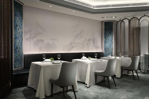 a dining room with white tables and chairs at The Landis Taipei in Taipei
