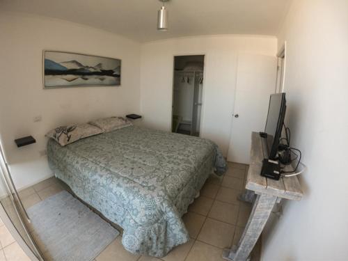 1 dormitorio con 1 cama y TV de pantalla plana en Departamento Edificio Playa Blanca, en La Serena