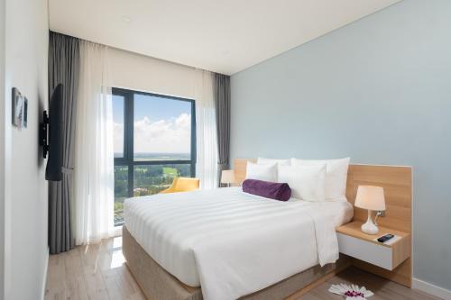 a bedroom with a white bed and a large window at Carinae Danang Hotel in Danang