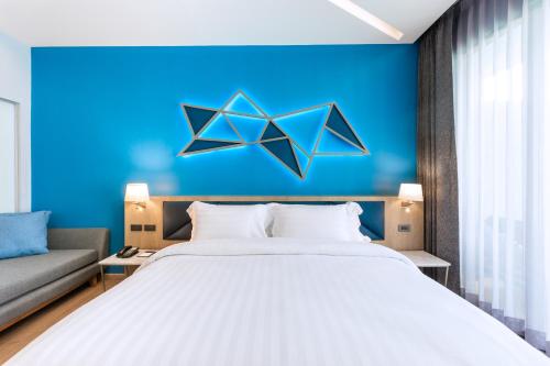 a bedroom with a large bed and a blue wall at BlueSotel SMART Krabi Aonang Beach - Adults only in Ao Nang Beach