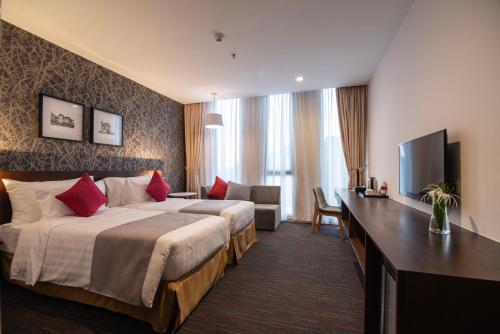 a hotel room with two beds and a television at Ramada Meridin Johor Bahru in Nusajaya