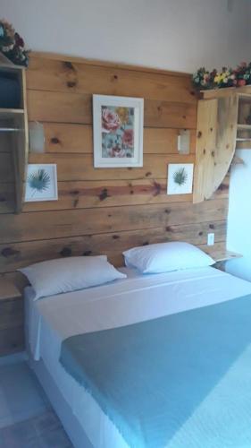 a bedroom with a large white bed with wooden walls at Pousada Bar Café Algas Marinhas in Praia do Forte