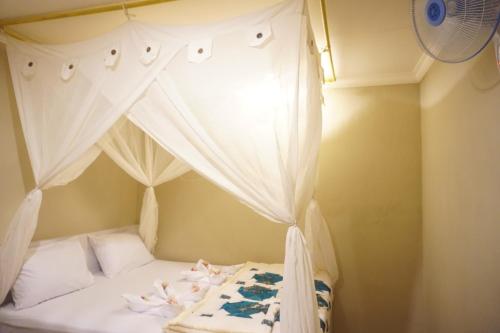 een slaapkamer met een hemelbed en witte gordijnen bij Damuh Guest House in Ubud