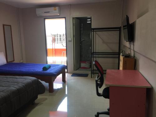 a room with a bed and a desk and a table at SMILE HOME GUESTHOUSE in Rayong