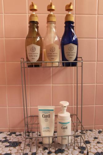 a rack with fourentedentedentedentedented bottles on a pink tiled bathroom at Guest House Toranjyo-lit in Tamano