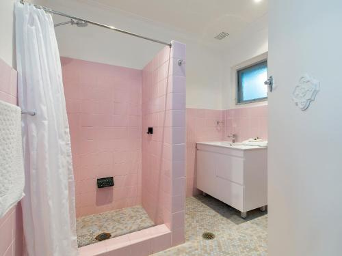 a pink bathroom with a shower and a sink at Dutchies Motel Nelson Bay in Nelson Bay