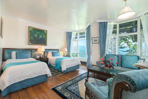 a bedroom with two beds and a couch at The Elgin Silver Oaks - Heritage Resort & Spa in Kalimpong