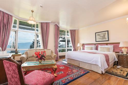 a bedroom with a bed and a chair and a table at The Elgin Silver Oaks - Heritage Resort & Spa in Kalimpong