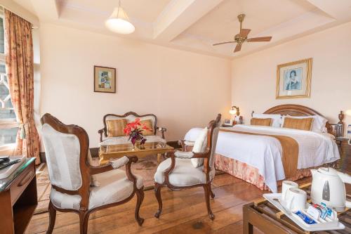 a bedroom with a bed and a table and chairs at The Elgin Silver Oaks - Heritage Resort & Spa in Kalimpong