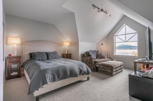 a bedroom with a bed and a chair and a window at Kelowna Discovery in Kelowna