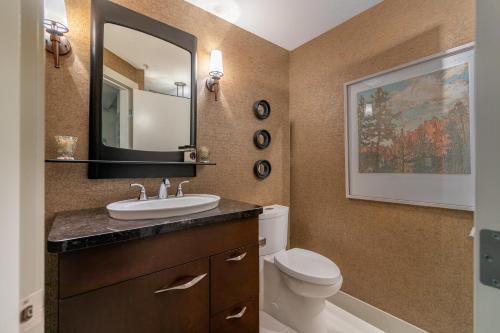 a bathroom with a sink and a toilet and a mirror at Kelowna Discovery in Kelowna