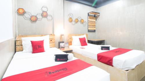 two beds in a room with red and white sheets at RedDoorz Plus @ Taft North Mandurriao in Iloilo City