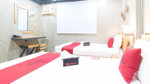 a room with two beds and a table and a desk at RedDoorz Plus @ Taft North Mandurriao in Iloilo City
