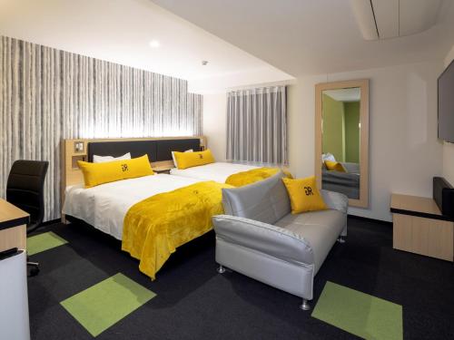 een slaapkamer met een groot bed met gele kussens en een bank bij Green Rich Hotel Kurashiki Ekimae (Artificial hot spring Futamata Yunohana) in Kurashiki
