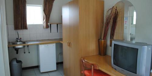 une cuisine avec une table et une télévision sur un bureau dans l'établissement Garden View Lodge, à Mahikeng