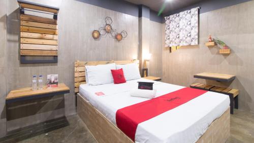 a bedroom with a large bed with a red blanket at RedDoorz Plus @ Taft North Mandurriao in Iloilo City