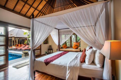 um quarto com uma cama de dossel e uma piscina em Villa Saffron Seminyak Bali em Seminyak