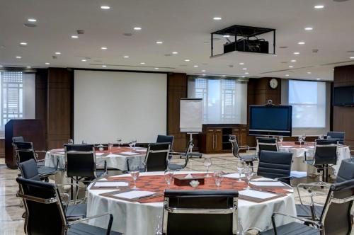 a conference room with tables and chairs and a screen at Crowne Plaza Madinah by IHG in Al Madinah