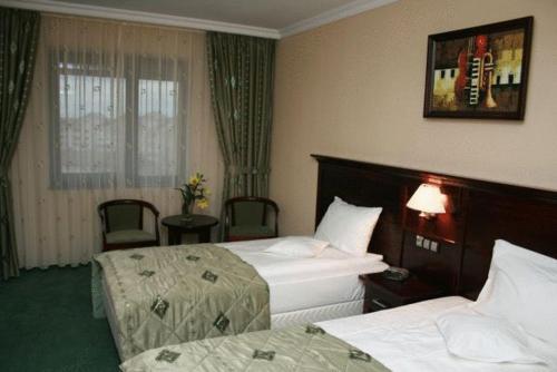 a hotel room with two beds and a window at Hotel Rapsodia City Center in Botoşani