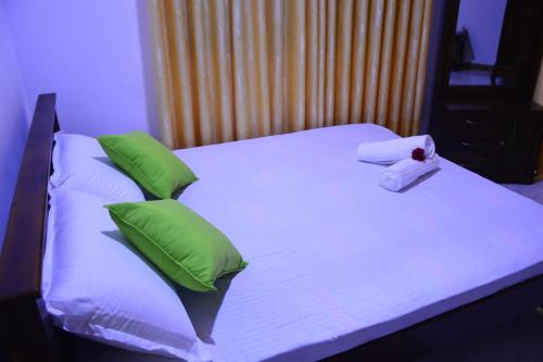 a bed with green pillows and a towel on it at Seven Luck Palace in Kandy