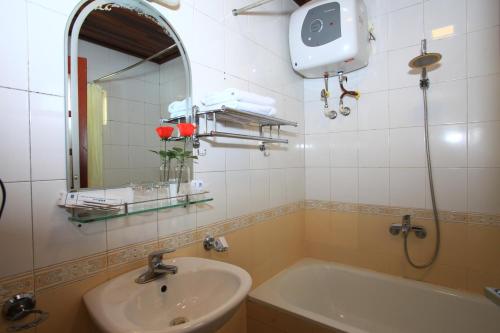 uma casa de banho com um lavatório, uma banheira e um espelho. em ATS Hotel em Hanói