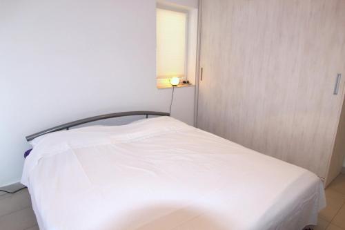a white bed in a small room with a window at Apartment Doder in Pag