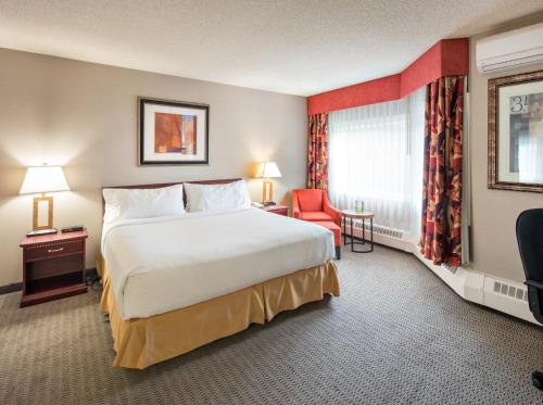 a hotel room with a large bed and a red chair at Holiday Inn Express Red Deer, an IHG Hotel in Red Deer