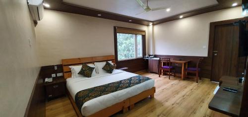 a bedroom with a bed and a desk and a window at Hotel Buddha House Himalayan Brothers in Dharamshala