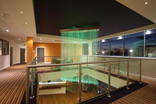 a glass staircase in a building with a pool at Holiday Inn Huntingdon Racecourse by IHG in Huntingdon
