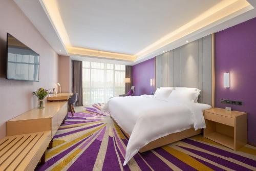a hotel room with a large bed and purple walls at Echarm International Hotel Guangzhou Baiyun International Airport Huadu Plaza Branch - Free Deliver Service to Guangzhou Baiyun International Airport & Free Deliver Service to Canton Fair Complex During Canton Fair Period in Huadu