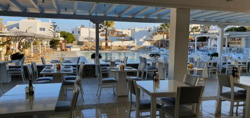 a restaurant with white tables and chairs and a pool at Yiannaki Hotel in Ornos