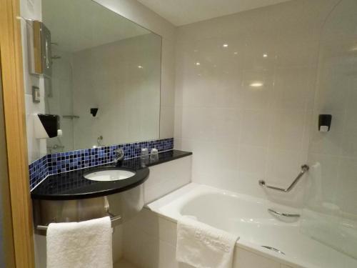 a bathroom with a tub and a sink and a mirror at Holiday Inn Express Pamplona, an IHG Hotel in Mutilva Baja