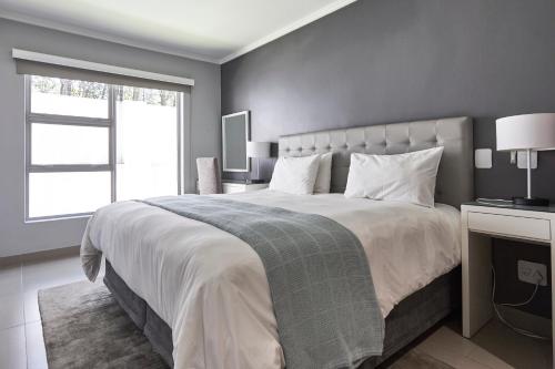 a bedroom with a large bed with a large window at The Residency Hurlingham in Johannesburg