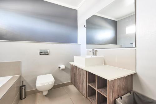 a white bathroom with a sink and a toilet at The Residency Hurlingham in Johannesburg