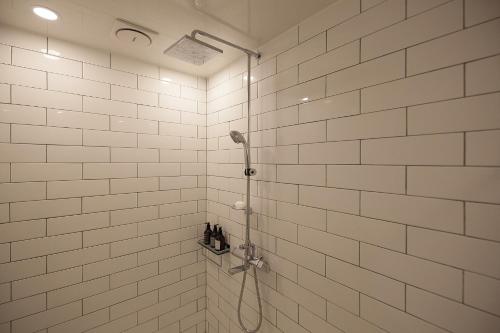 a white tiled shower with a shower head in a bathroom at Gray Hotel Busan Station in Busan
