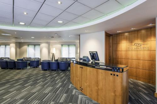 a conference room with a reception desk and blue chairs at Holiday Inn Oxford by IHG in Oxford