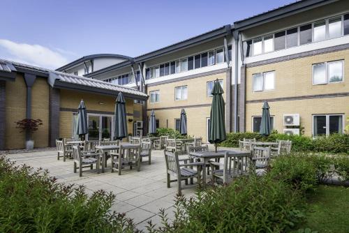 a patio with tables and umbrellas in front of a building at Holiday Inn Oxford by IHG in Oxford