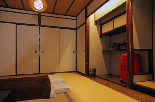 a bedroom with a bed and a bunk room with a red suitcase at Guesthouse KYOTO COMPASS in Kyoto