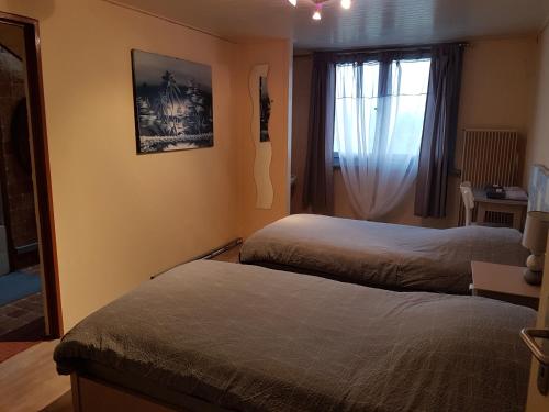 a bedroom with two beds and a window at Hotel de la Gare, Vendlincourt in Vendlincourt