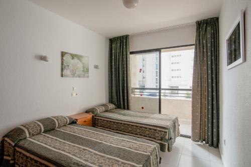a hotel room with two beds and a window at Luxmar Apartaments in Benidorm