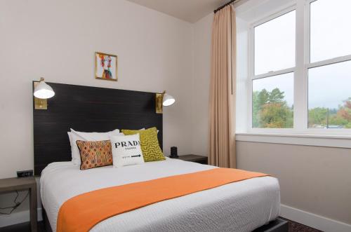 a bedroom with a bed with an orange and white comforter at The Dundee - A Trace Hotel in Dundee