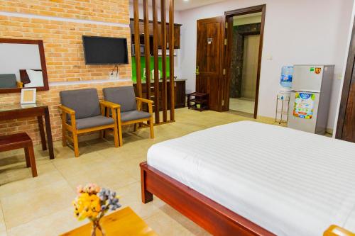 a bedroom with a bed and two chairs and a tv at Căn Hộ dịch vụ cao cấp Sân Bay Tân Sơn Nhất in Ho Chi Minh City
