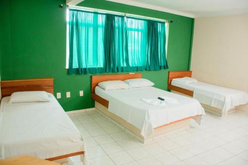 a bedroom with two beds and a green wall at Hotel Dez De Julho in Manaus